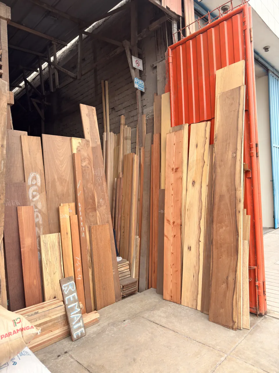 El portón naranja abierto, con tablas a la vista y un cartel que dice «Remate».