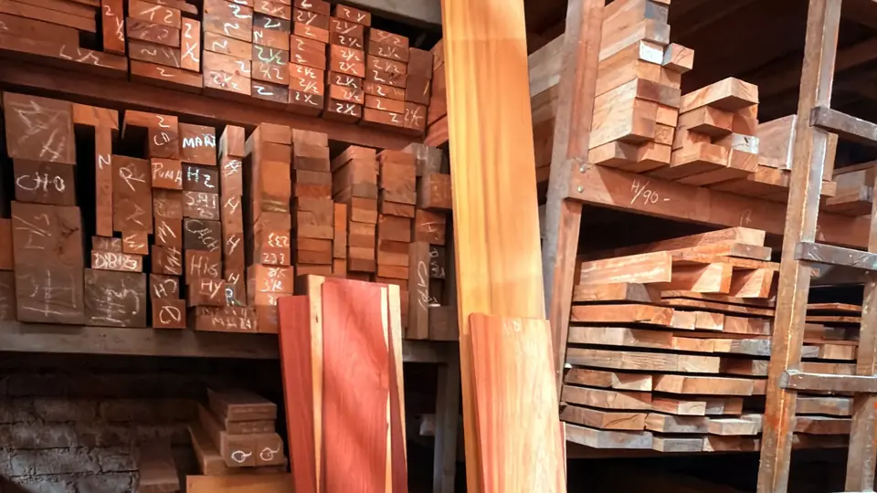 Estante de KIBA con piezas de madera apiladas; en la cabeza de cada una, su medida o su nombre escritos a tiza.